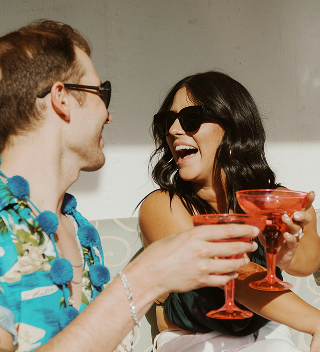 Two friends laughing and raising their glasses
