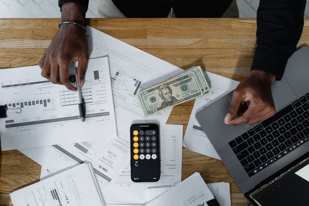A merchant working through rate sheets with a calculator and laptop
